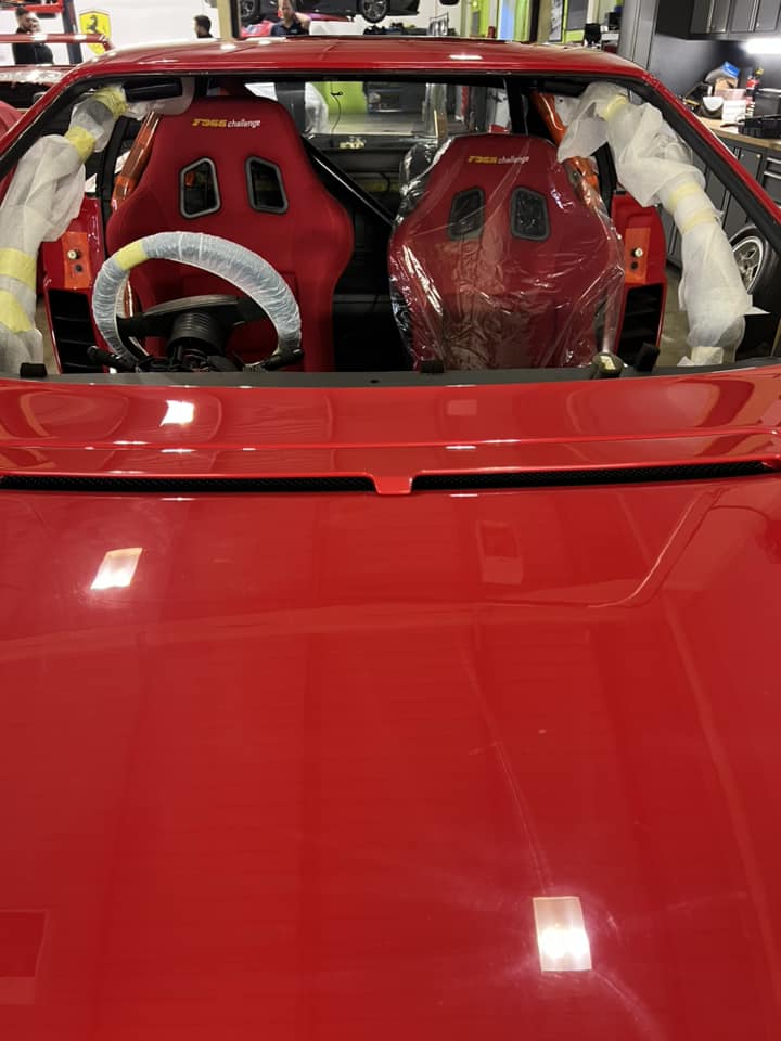 a red supercar with a windscreen being replaced in a garage in Canterbury